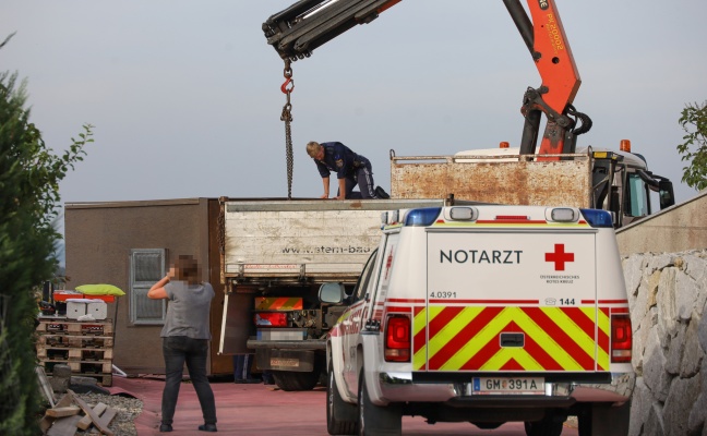 Person bei Verladearbeiten mit Kran in Laakirchen unter Container eingeklemmt